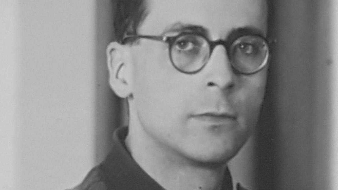 Schwarzweißporträt von Arnold Münster, ein junger Mann in Uniform und Brille.