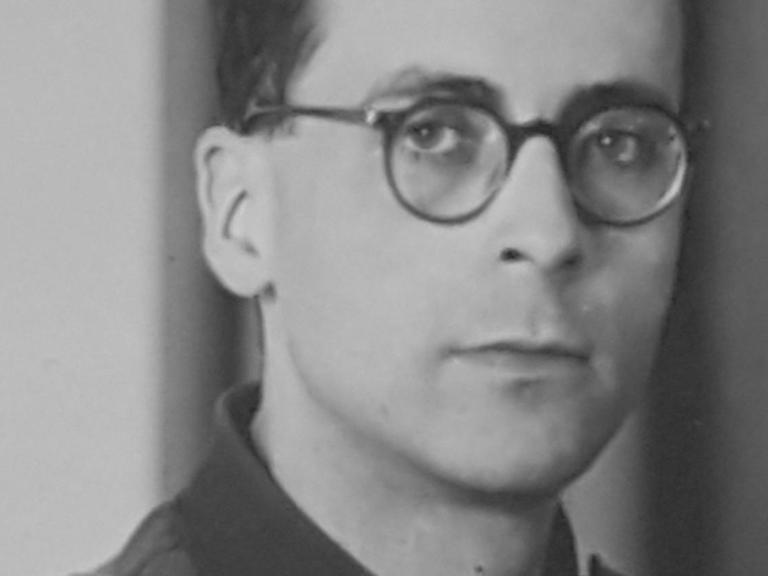 Schwarzweißporträt von Arnold Münster, ein junger Mann in Uniform und Brille.