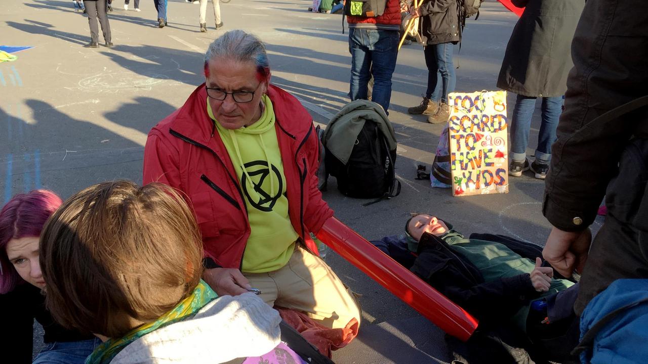 Werner Philippi kniet auf der Straße während eines Klimastreiks.