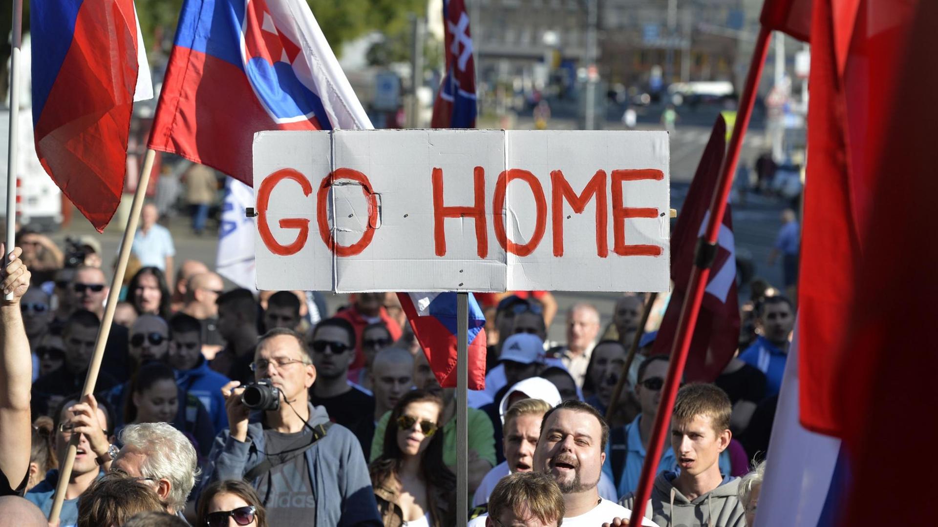 Teilnehmer einer Demonstration gegen Flüchtlinge in der slowakischen Hauptstadt Bratislava halten Flaggen und ein Banner mit der Aufschrift "Go Home" hoch.