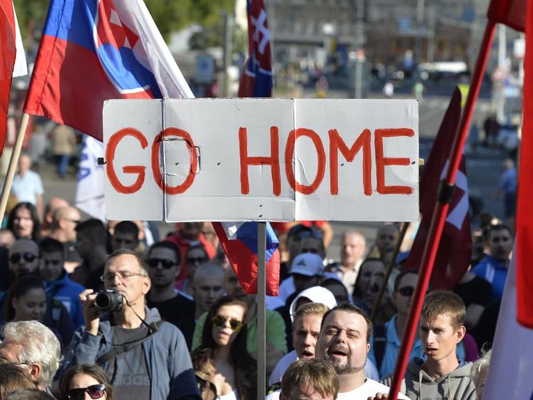 Teilnehmer einer Demonstration gegen Flüchtlinge in der slowakischen Hauptstadt Bratislava halten Flaggen und ein Banner mit der Aufschrift "Go Home" hoch.