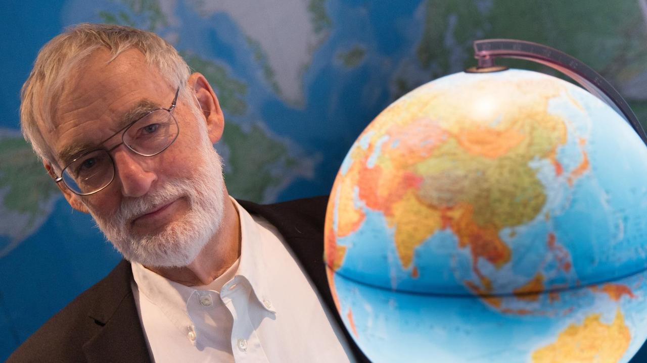 Der Umweltökonom Dennis Meadows hält am 21.04.2015 in Hamburg vor einer Weltkarte einen Globus in der Hand. 