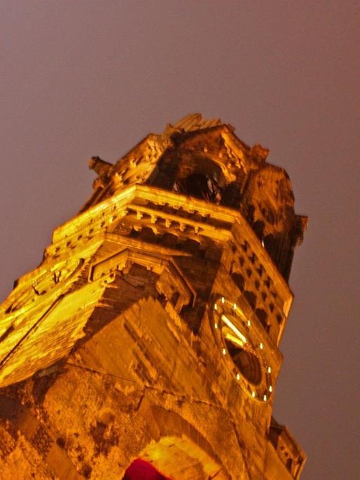 Der neue wie der historische Turm der Kaiser-Wilhelm-Gedächtnis-Kirche wird nachts strahlend illuminiert.