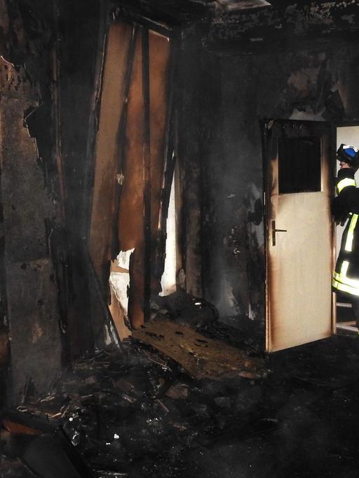 Ein Feuerwehrmann löscht am 08.10.2015 in einer geplanten Flüchtlingsunterkunft in Grimma (Sachsen) einen Brand. Foto: Frank Schmidt/dpa