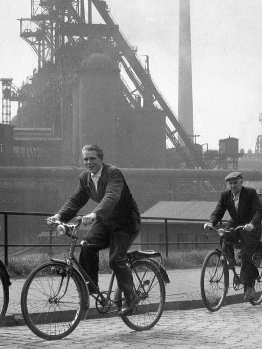 Arbeiter auf ihren Fahrrädern während des Schichtwechsels beim Hüttenwerk Oberhausen im Jahr 1957.