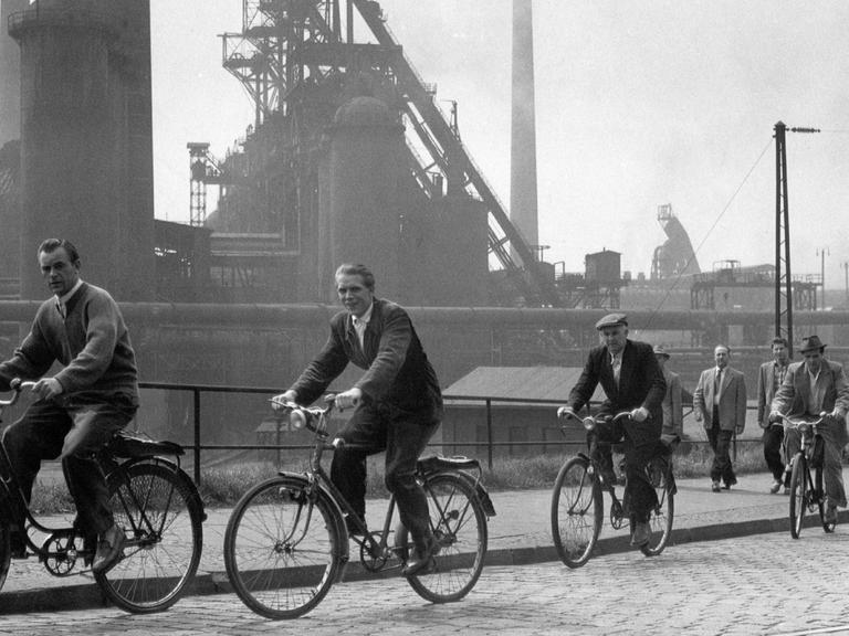 Arbeiter auf ihren Fahrrädern während des Schichtwechsels beim Hüttenwerk Oberhausen im Jahr 1957.