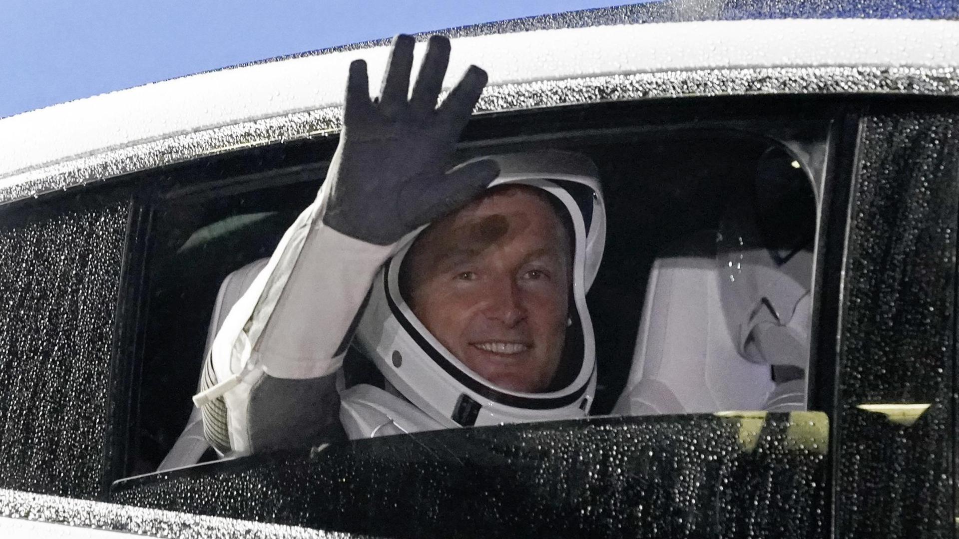 Matthias Maurer winkt aus einem Auto-Fenster.