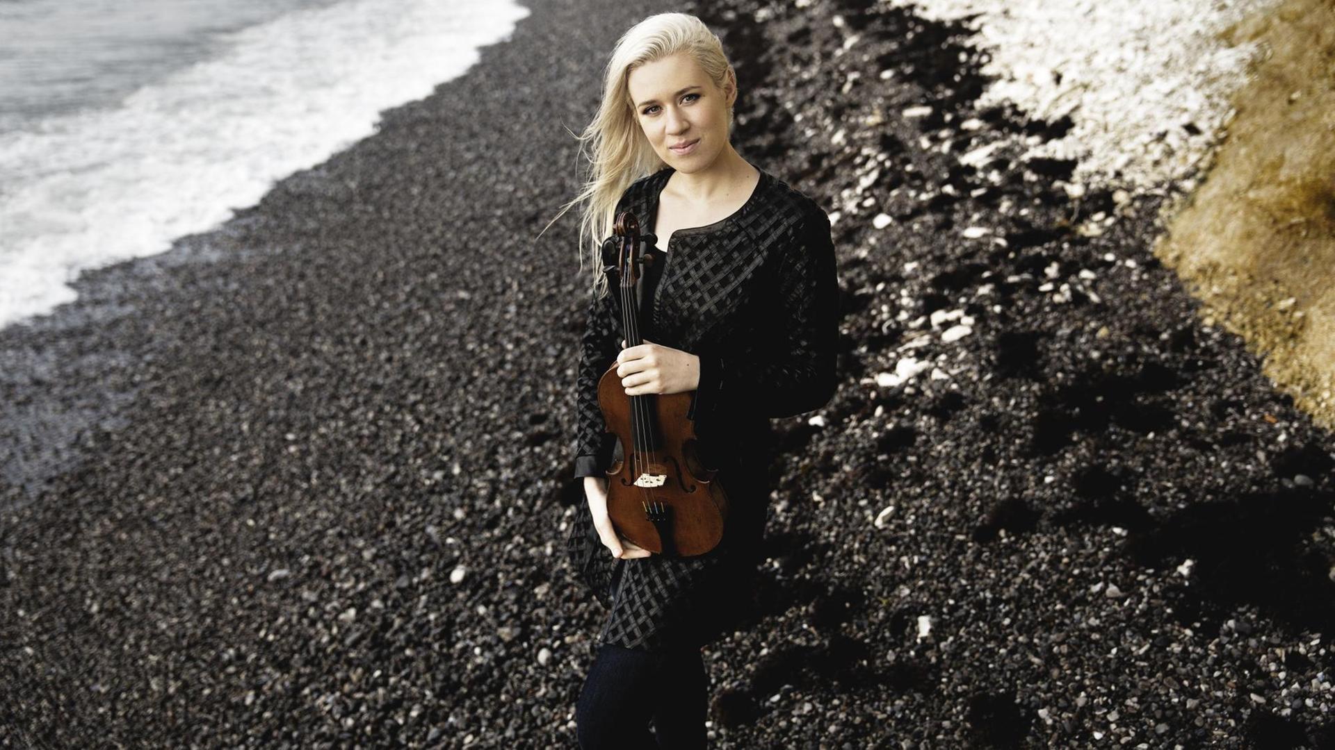 Die norwegische Geigerin Eldbjørg Hemsing steht mit Geige am Strand