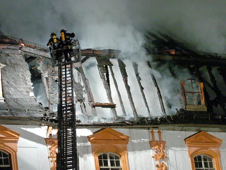 Rauch steigt aus dem Dachstuhl der Herzogin Anna Amalia Bibliothek in Weimar, zwei Feuerwehrleute auf einer Leiter löschen.