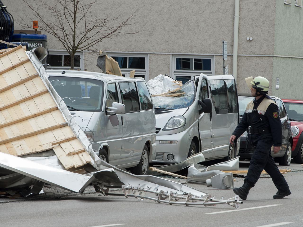 Ein Feuerwehrmann läuft am 31.03.2015 in Weilheim (Bayern) an einem stark beschädigtem Auto vorbei