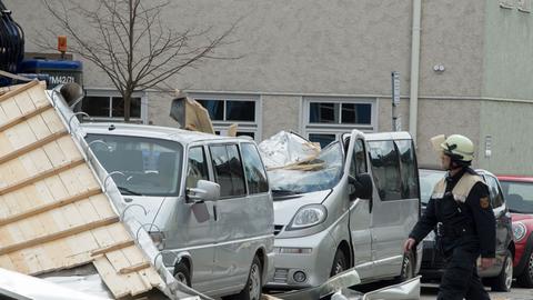 Ein Feuerwehrmann läuft am 31.03.2015 in Weilheim (Bayern) an einem stark beschädigtem Auto vorbei