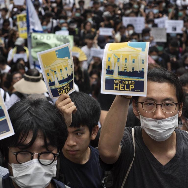 Protestanten in Hongkong halten Schilder hoch, um die Staaten der G20 um Hilfe zu bitten.