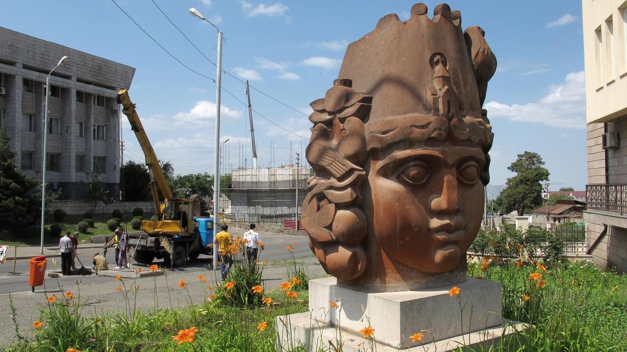 Ein Skulptur, die einen Frauenkopf darstellt, steht am "Platz der armenischen Wiedergeburt" im Zentrum von Stepanakert in der Region Bergkarabach, dahinter sind Bauarbeiten im Gange.