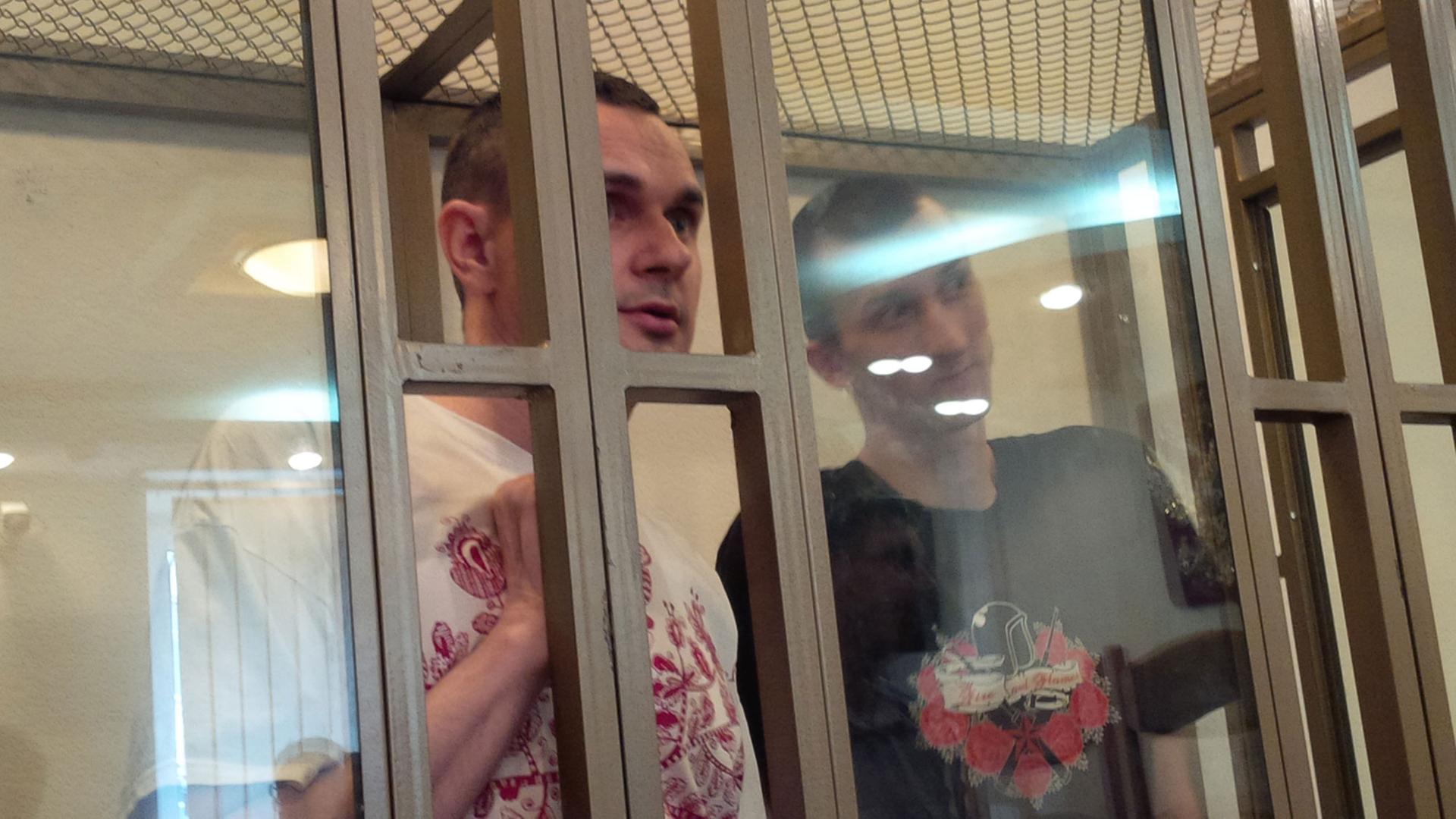 Der ukrainische Filmregisseur Oleg Senzow und der Mitangeklagte Alexander Koltschenko in einem Gitterkäfig vor Gericht in Russland im August 2015