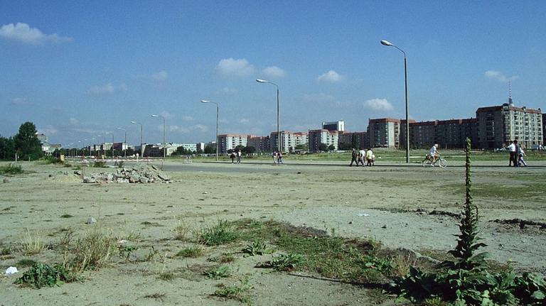 Mauerbrache in Berlin Anfang der 90er-Jahre. Zu sehen ist unbebautes Gelände in Berlins Mitte. Im Hintergrund stehen DDR-Neubauten und der Fernsehturm. 