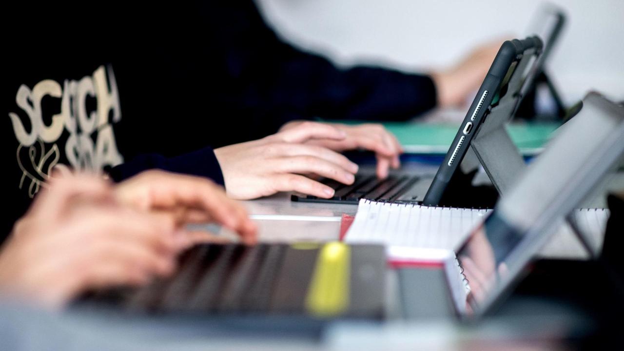 Mehrere Schüler sitzen während des Unterrichts vor Tablet-Computern.