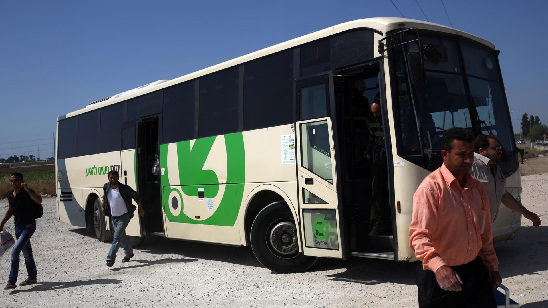 Mehrere Männer verlassen einen weiß-grünen Bus.