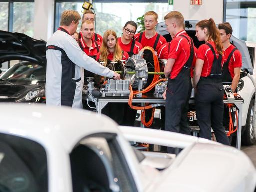 Ausbilder Carsten Pohle (l) erläutert Auszubildenden im 2. Lehrjahr die Funktionsweise eines Hybridantriebes an einem Modellaufbau im Porsche Ausbildungszentrum