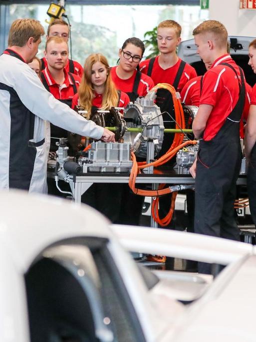 Ausbilder Carsten Pohle (l) erläutert Auszubildenden im 2. Lehrjahr die Funktionsweise eines Hybridantriebes an einem Modellaufbau im Porsche Ausbildungszentrum
