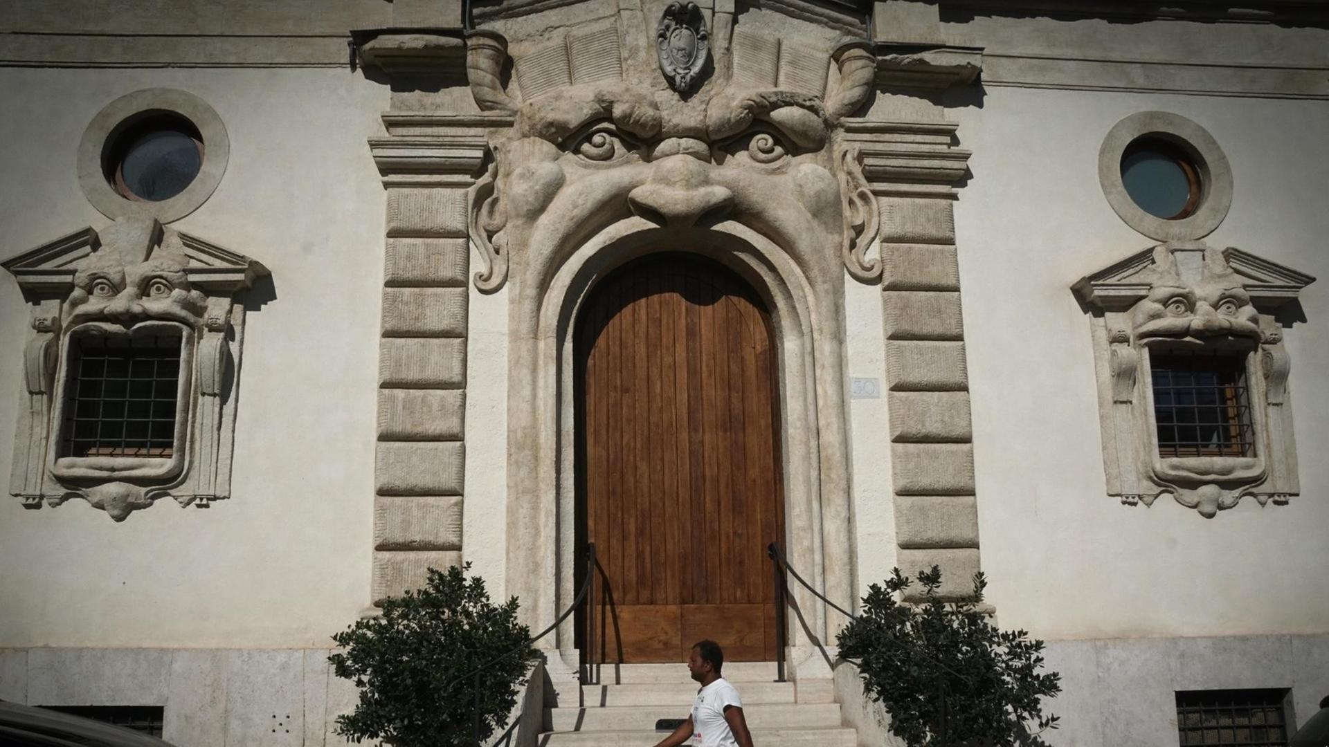 Ein Passant geht am Palazzo Zuccari vorbei, dessen Eingangstür und Fenster wie Münder von Gesichtern geformt sind.