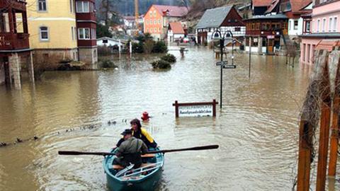 Ein Feuerwehrmann fährt eine Postfrau mit einem Boot durch den überfluteten Ort Rathen nahe Dresden.