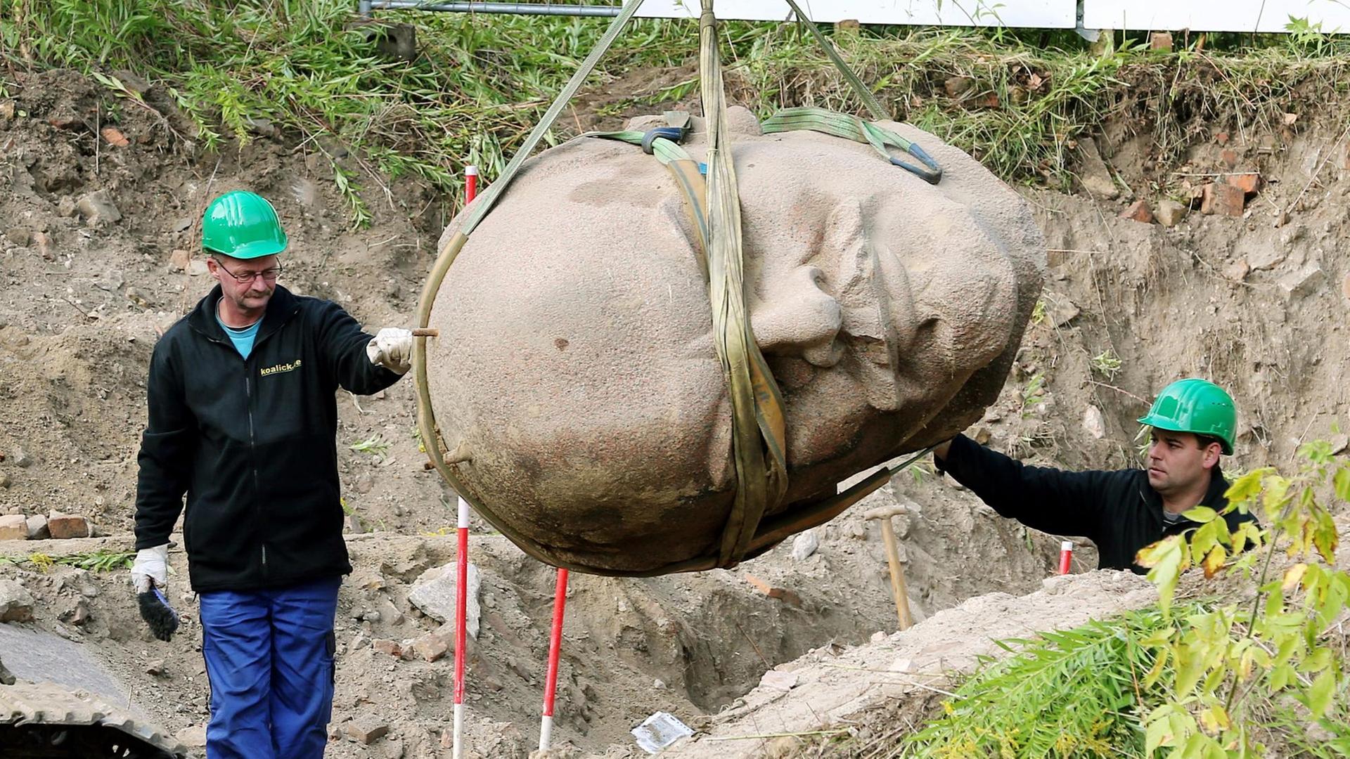 Arbeiter einer Spezialfirma sichern in einem Waldstück am Müggelsee in Berlin den an einem Kran hängenden Kopf einer Lenin-Statue.