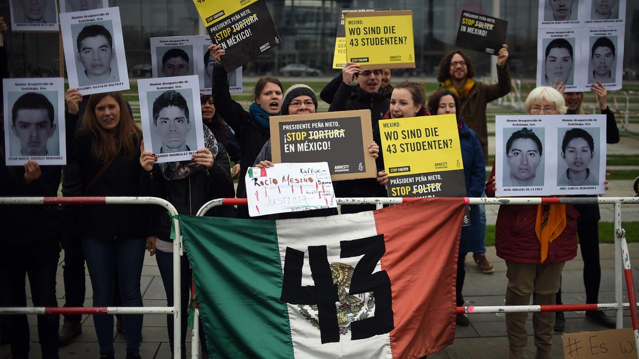 Mitglieder von Amnesty International protestieren in Berlin gegen Folter und zeigen Bilder von 43 verschwundenen Studenten.