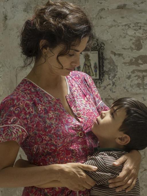 Die Schauspieler Penélope Cruz und Asier Flores in einer liebevollen Filmszene, in der die Mutter ihren kleinen Sohn umarmt.
