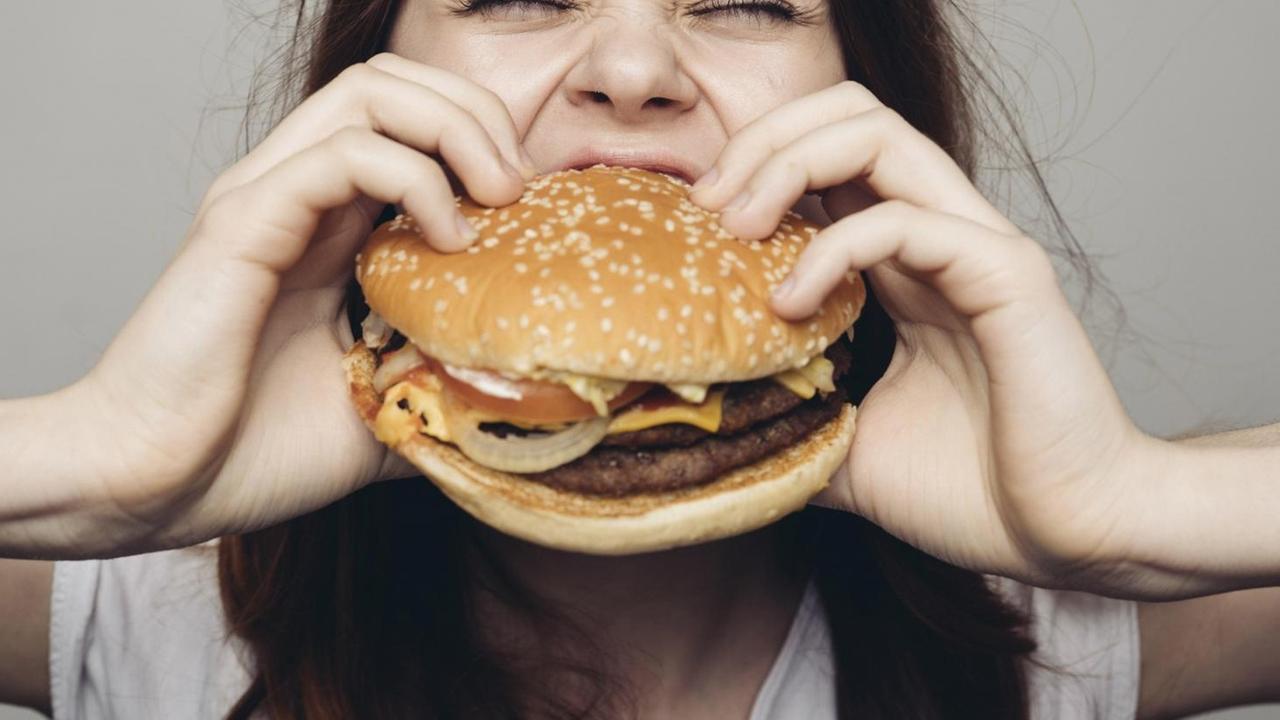 Eine Frau beißt in einen Cheeseburger.