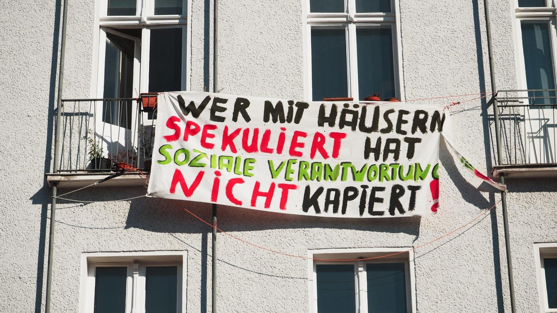Wer mit Häusern spekuliert hat soziale Verantwortung nicht kapiert!" steht auf einem Transparent an einer Hausfassade in Berlin im Bezirk Schöneberg am 19.03.2015. Foto: Wolfram Steinberg/dpa.
