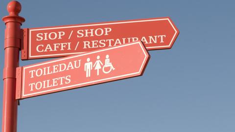 Zweisprachiger Wegweiser auf Englisch und Walisisch zu Restaurant, Laden und Toiletten in Wales