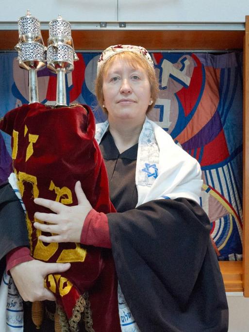Antje Yael Deusel steht mit der Tora ein einer nüchtern eingerichteten Synagoge.