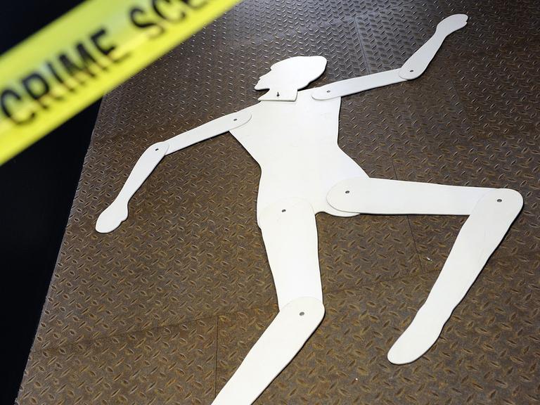 Das Bild zeigt die Silhouette einer Frau an einem Tatort, der durch ein gelbes Band mit der Schrift "Crime Scene" abgetrennt ist.