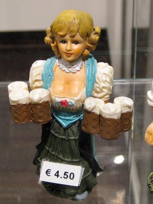 Ein Souvenirhändler am Hauptbahnhof in München bietet Trachten-Figuren zum Verkauf.