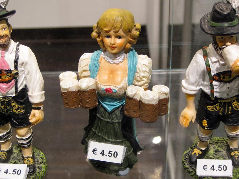 Ein Souvenirhändler am Hauptbahnhof in München bietet Trachten-Figuren zum Verkauf.