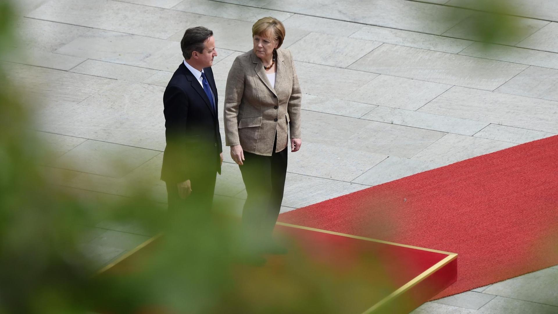 Der britische Premier David Cameron und Bundeskanzlerin Angela Merkel stehen auf einem roten Teppich in Berlin.