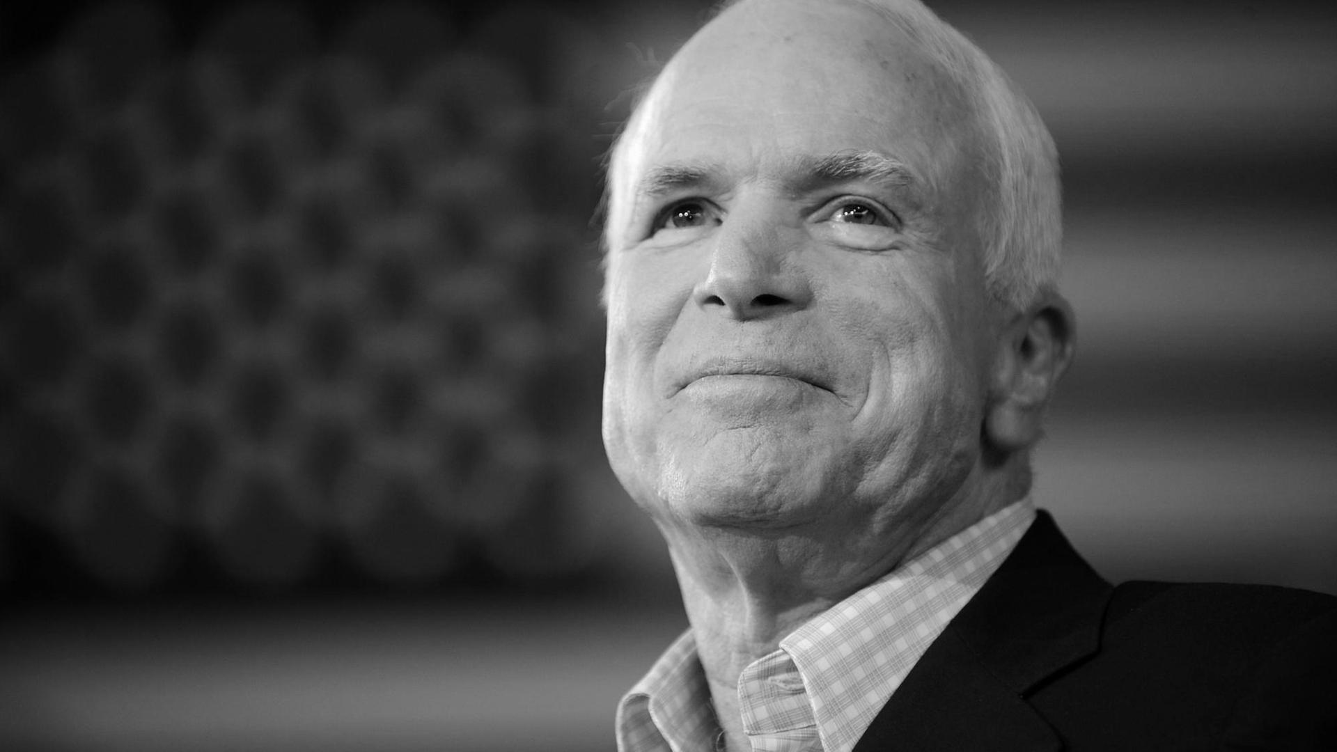 Nahaufnahme des US-Senators John McCain aus dem Jahr 2008. Im Hintergrund verschommen die US-Flagge.