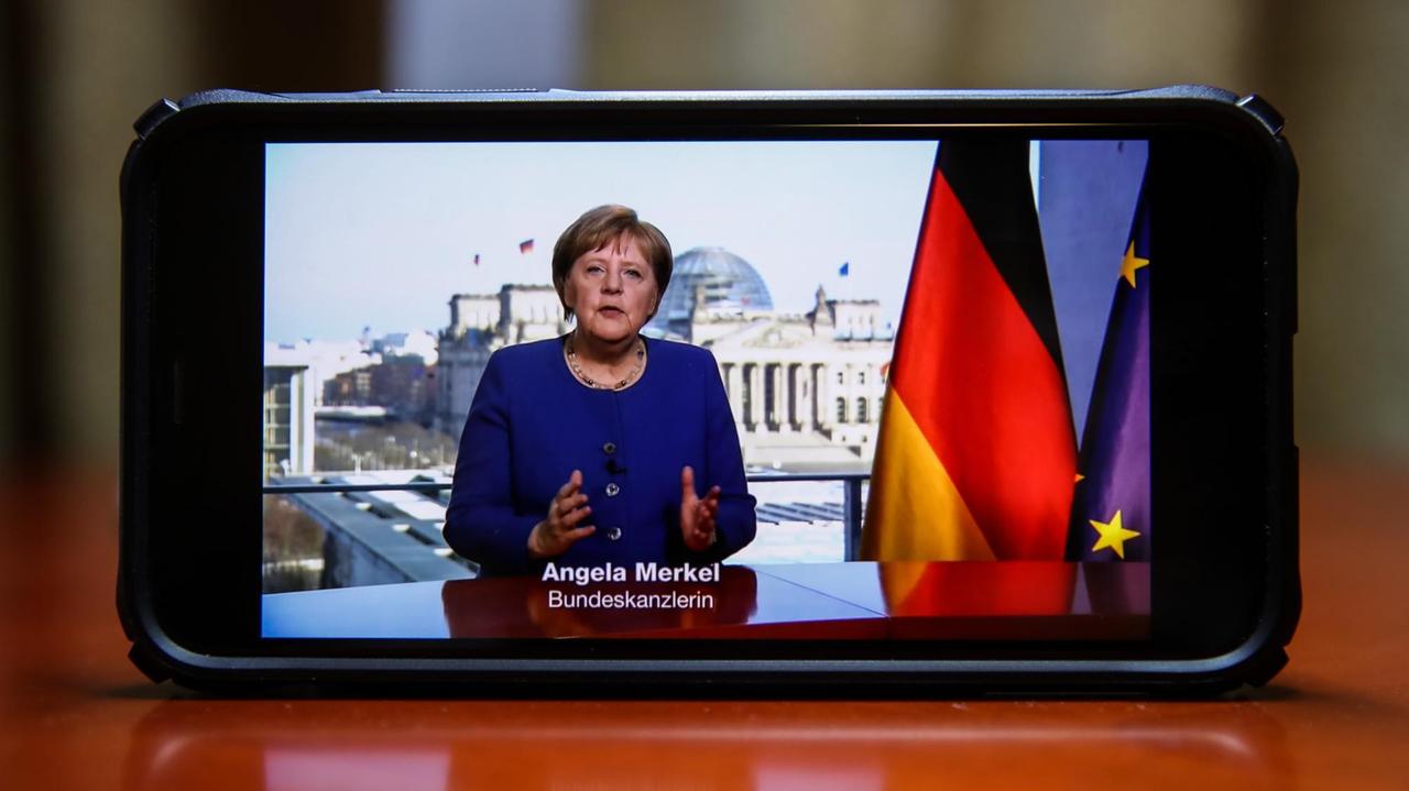 Auf einem Smartphone läuft die Fernsehansprache von Bundeskanzlerin Angela Merkel zur Coronakrise.