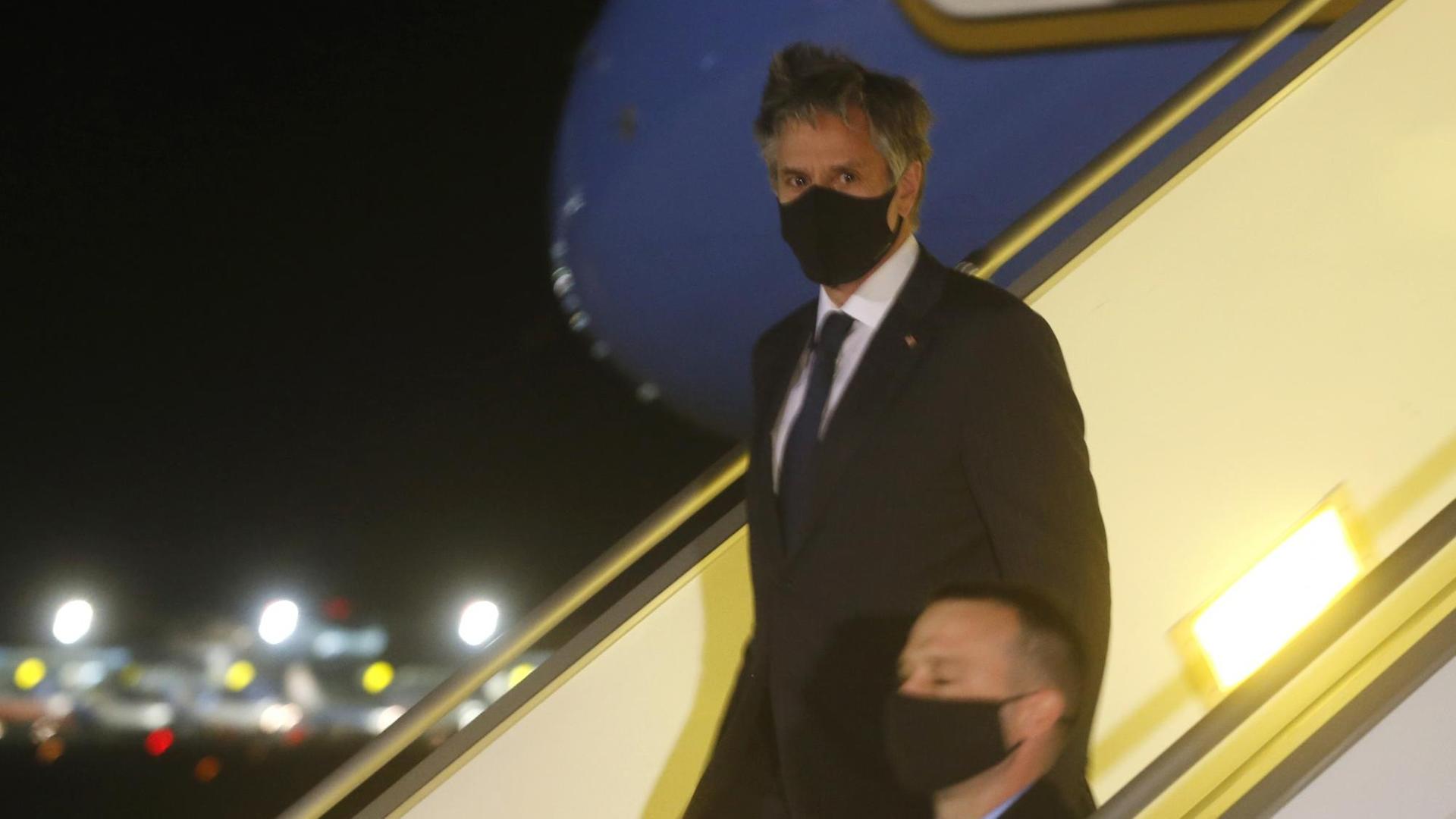 US-Außenminister Antony Blinken mit schwarzem Mund-Nasenschutz beim Verlassen eines Flugzeugs auf der Gangway.