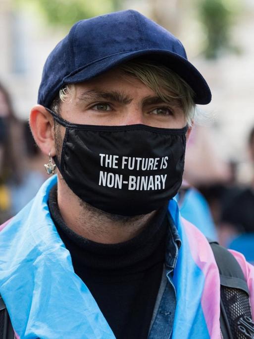 Demonstration für Transrechte in London. Ein junger Mensch trägt einen schwarzen Mundschutz mit der Aufschrift. "The future in non-binary".