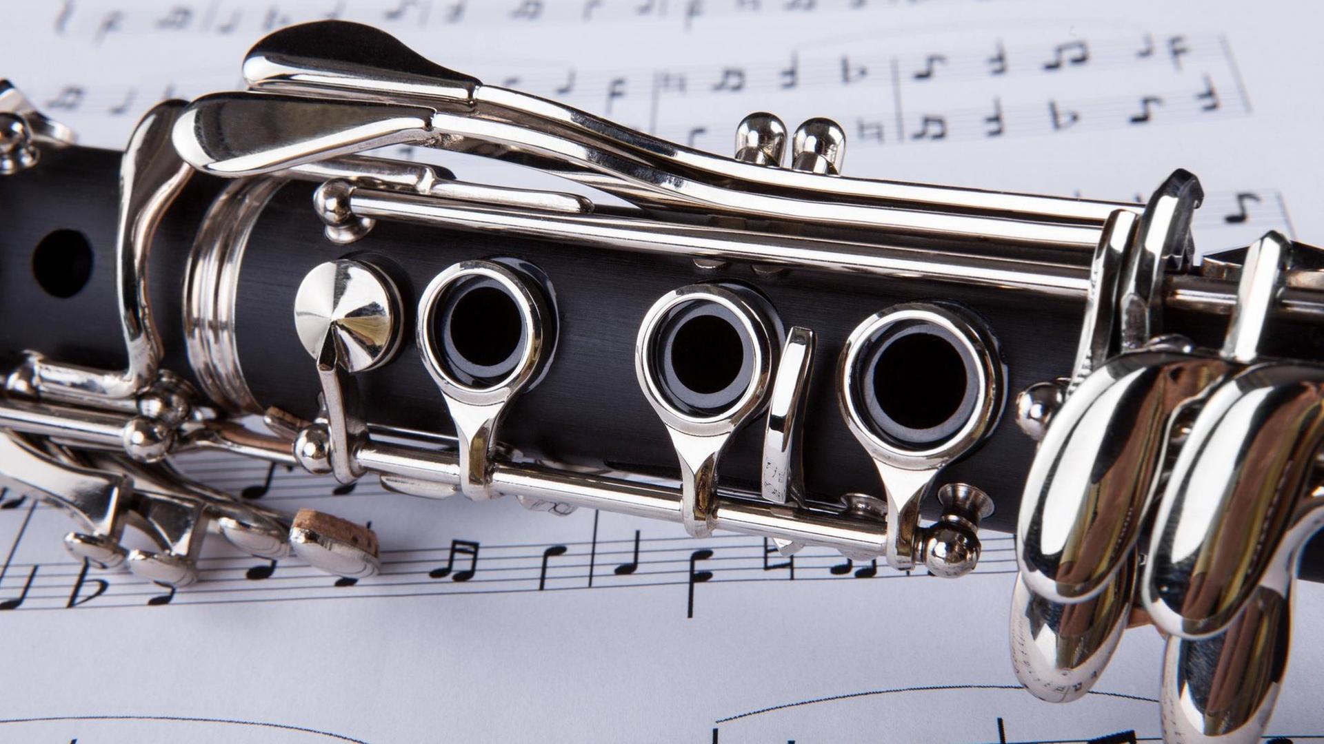 Detailansicht einer Klarinette, die auf gedruckten Noten liegt.