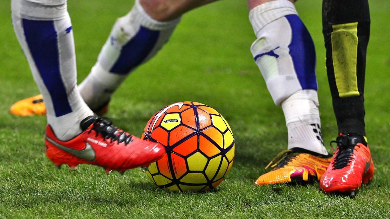 Füße von Fußballspielern und ein bunter Ball