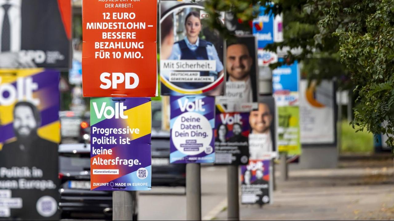 Plakate von verschiedenen Parteien  hängen an Laternenpfählen.