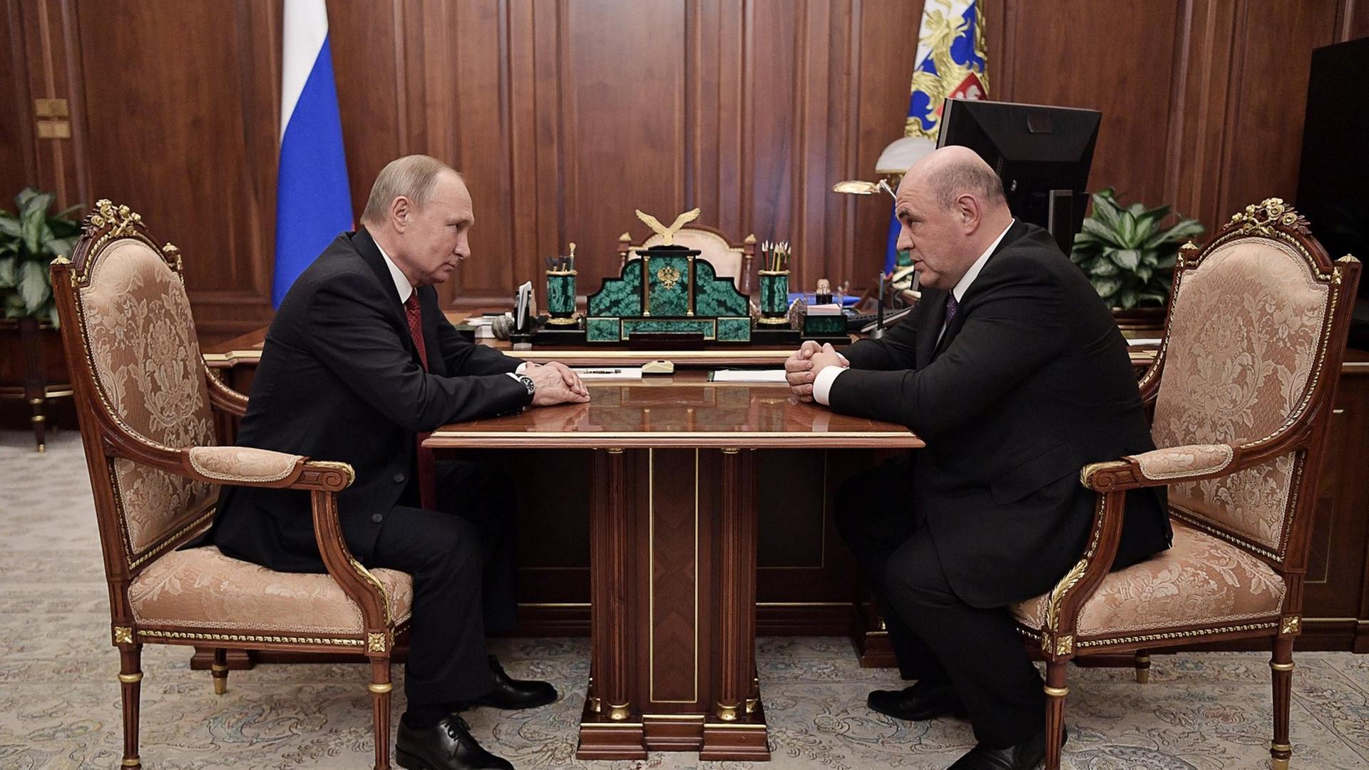 Russlands Präsident Wladimir Putin sitzt an seinem Schreibtisch dem neuen bisherigen Chef der föderalen Steuerbehörde, Michail Mischustin gegenüber.