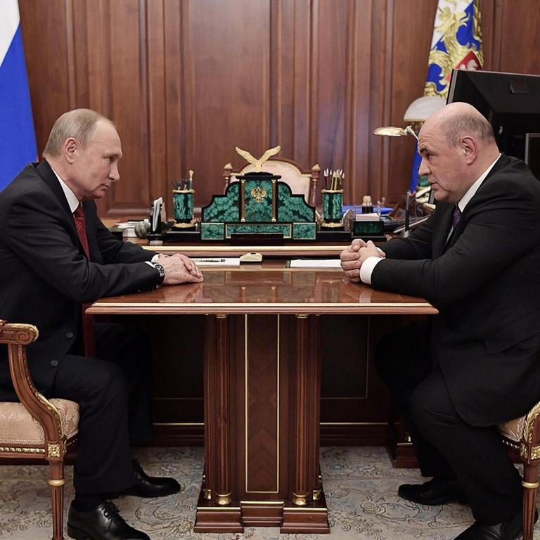 Russlands Präsident Wladimir Putin sitzt an seinem Schreibtisch dem neuen bisherigen Chef der föderalen Steuerbehörde, Michail Mischustin gegenüber.