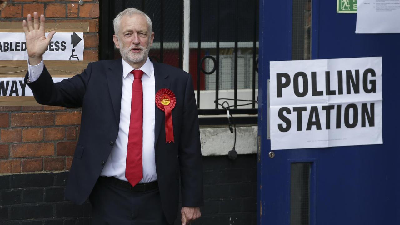 Labour-Chef Jeremy Corbyn steht vor seinem Wahllokal und winkt.
