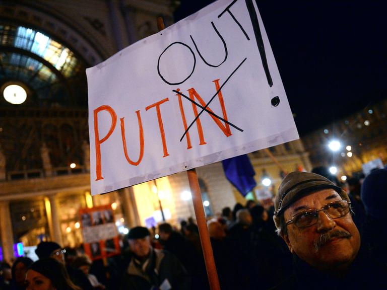 Ein Demonstrant in Budapest hält ein Schild mit der Aufschrift "Putin Out"