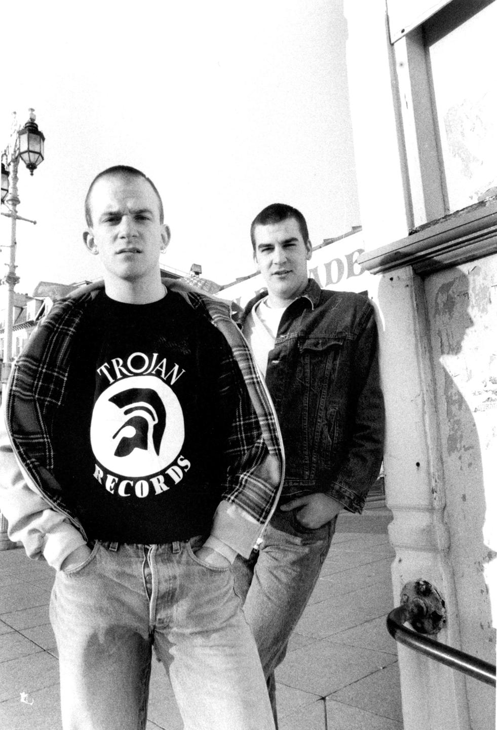 Zwei Jugendliche Skinheads in den 80ern. Einer trägt ein T-Shirt des legendären Reggae-Labels "Trojan Records".