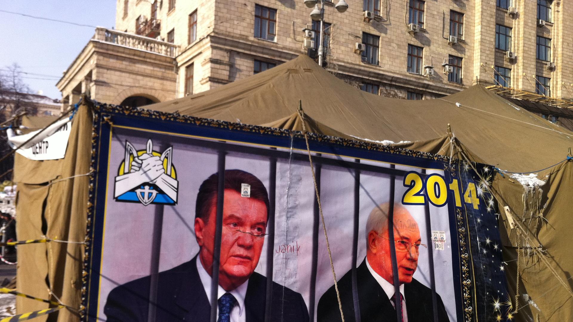 Präsident Janukowitsch und Regierungschef Asarow (r) werden am 26.01.2014 an einem Zelt auf dem Prachtboulevard Kreschtschatik in Kiew, Ukraine, hinter Gittern dargestellt.