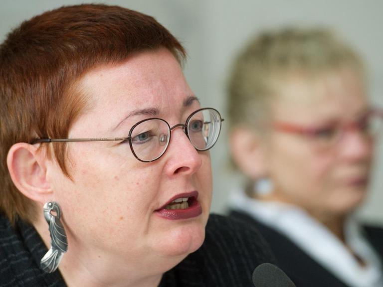 Martina Weyrauch (l), Leiterin der Brandenburgischen Landeszentrale für politische Bildung, spricht in ein Mikrofon, im Hintergrund verschwommen eine andere Frau.